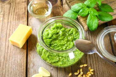 Ev yapımı pesto sos. Malzemeler. Peynir, sarımsak, fesleğen, çam fıstığı, zeytin yağı eski ahşap masa.