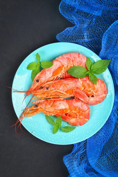 Stock image Large royal raw frozen prawns on a blue plate with thyme and basil on a concrete table. Red shrimps. Top view.