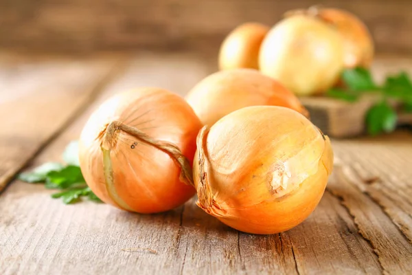 Gele ui met peterselie op een houten tafel. — Stockfoto