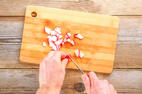 Мужские руки порезали колбасу Болоньи на разделочной доске на старом деревянном столе . — стоковое фото