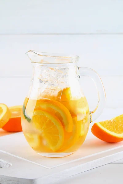 Agua de desintoxicación naranja en una jarra sobre una mesa de madera blanca. Comida saludable, bebidas . —  Fotos de Stock
