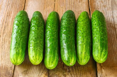 Eski bir ahşap masa üzerinde bir yaprak taze salatalık.