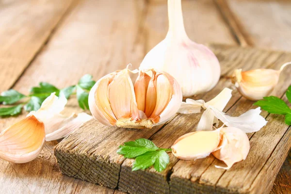 Heads of garlic with parsley on a wooden table.