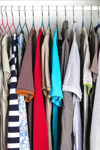 Men\'s and women\'s clothing on silicone hangers in the wardrobe closet. The same shoulders. Storage organization. Order and cleanliness. Quarantine, self-isolation, housework.