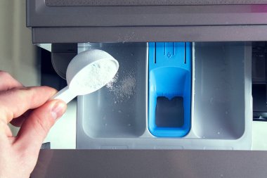 Bir adam sabun tozu döker, saç kremi döker, çamaşır makinesinin tepsisine renk katar..