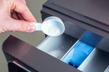 Bir adam sabun tozu döker, saç kremi döker, çamaşır makinesinin tepsisine renk katar..