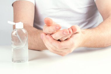 Küçük portatif antibakteriyel el dezenfektanı kullanan bir adam..