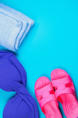 Terlikler, mayo, mavi pastel arka planda havlu. Dinlen, seyahat et. Üst Manzara. Düz yatağı kopyala
