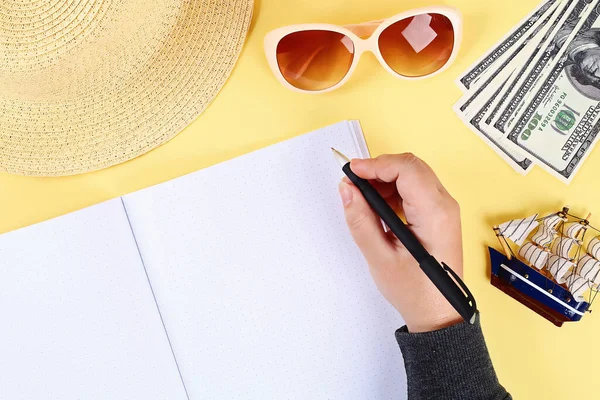Blank notepad on a yellow background, sun glasses, hat, money. Top view, flat lay. Mockup, copy space. Summer background travel