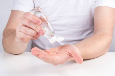 Küçük portatif antibakteriyel el dezenfektanı kullanan bir adam..