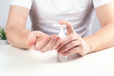 Küçük portatif antibakteriyel el dezenfektanı kullanan bir adam..