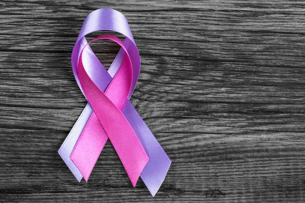 health symbol pink and lavender ribbon on wooden board background