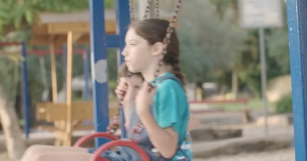 Niños balanceándose en swing — Vídeo de stock