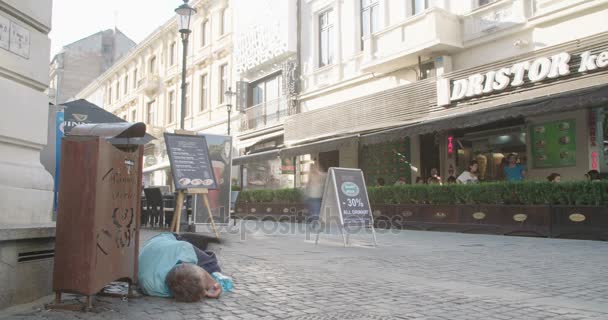 БУХАРЕСТ, Румыния - 5 АВГУСТА 2017: Бездомный лежит на оживленной улице — стоковое видео