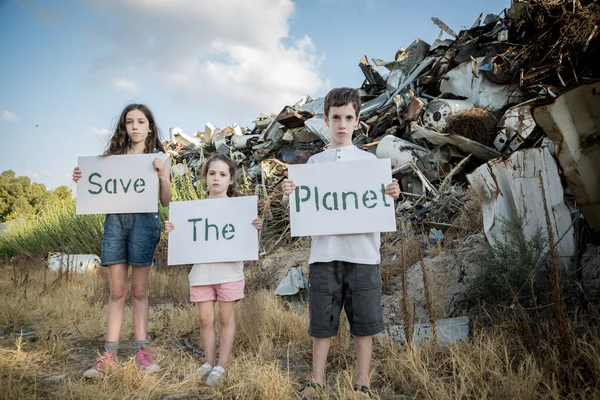 Gezegeni kurtarmak. küçük çocuklar büyük bir hurdalıkta ayakta elinde