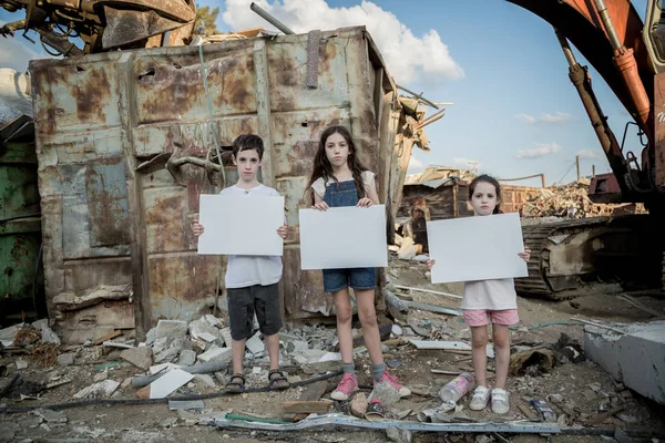 Save the planet. young kids holding signs standing in a huge junkyard