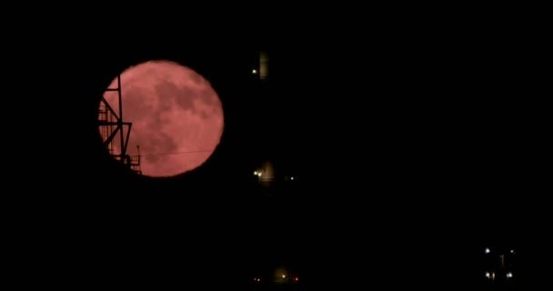 Luna piena rossa che sorge da dietro una grande raffineria di petrolio — Video Stock