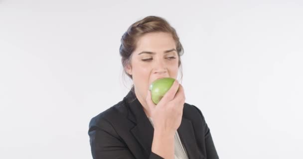 Mujer mordiendo y comiendo una manzana en un fondo de estudio blanco — Vídeos de Stock