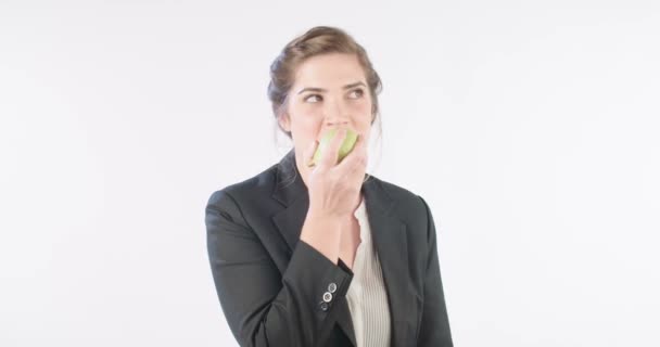 Kvinna som äter ett stort äpple på en vit studio bakgrund — Stockvideo