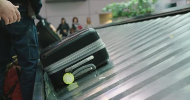 Pasajeros recogiendo equipaje de una cinta transportadora en el aeropuerto — Vídeo de stock