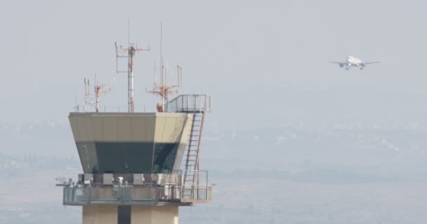 Airport control tower with airplane landing in the background — Stock Video