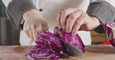 Kırmızı lahana dilimleyen şef bıçağının yavaş çekimde yakın çekimi.