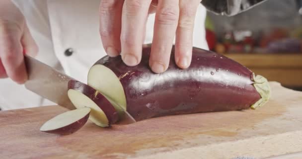 Mouvement lent gros plan d'un couteau de chef tranchant une aubergine — Video