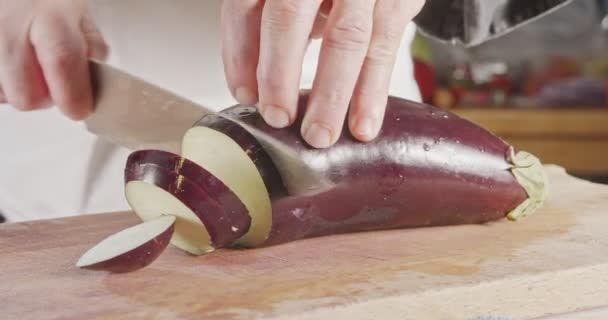 Zeitlupe Nahaufnahme eines Kochmessers, das eine Aubergine schneidet — Stockvideo