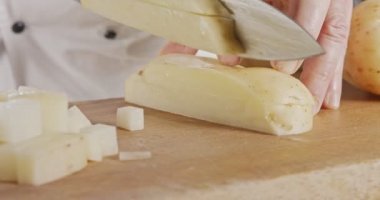 Bir şefin keskin büyük bir bıçakla patatesi dilimlemesi ağır çekimde.