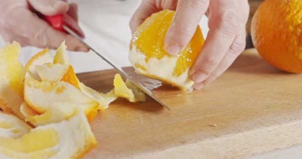 Nahaufnahme eines Kochmessers, das eine Orange schält und schneidet — Stockvideo