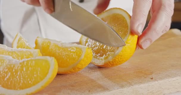 Primer plano de un cuchillo de chef pelando y cortando una naranja — Vídeo de stock