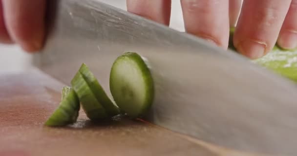 Macro shot of a large chef knife slicing a cucumber — Stock Video