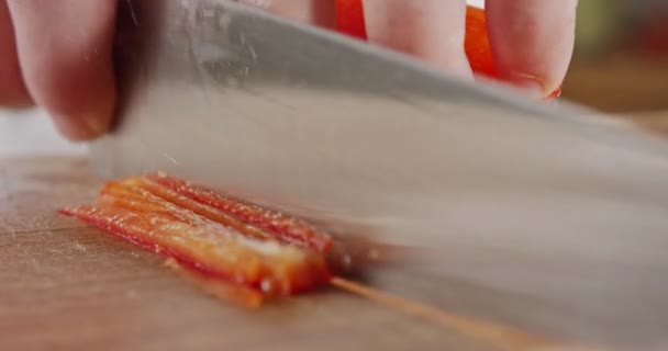 Macro extremo de un cuchillo de chef rebanando un pimiento rojo — Vídeos de Stock