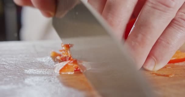 Extrém makró egy szakácskés szeletelő piros harangbors — Stock videók