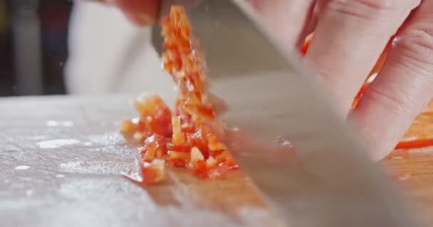 Extremes Makro eines Küchenmessers, das eine rote Paprika schneidet — Stockvideo