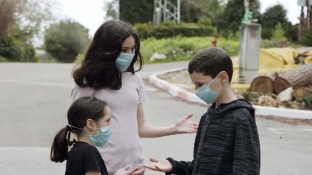 Pandemia de Coronavirus - niños caminando al aire libre con máscaras faciales para evitar la corona — Vídeo de stock