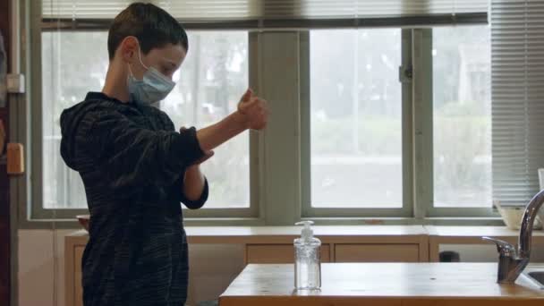코로나 유행성 얼굴 마스크를 쓴 코로나 범유행 소년, 코로나 바이러스 예방을 위해 손 소독 기를 사용 — 비디오