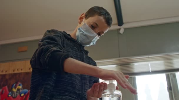 Хлопчик з короною пандемії з маскою обличчя за допомогою ручного санитизатора, щоб запобігти коронавірусу — стокове відео