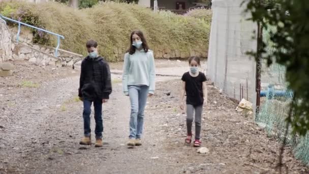Koronavirová pandemie - děti chodící venku s obličejovými maskami, aby se zabránilo nákaze — Stock video