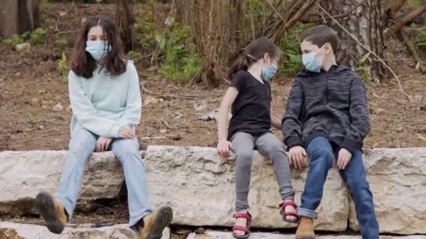 Coronavirus pandemie - kinderen dragen gezichtsmaskers om besmetting te voorkomen zittend verveeld — Stockvideo