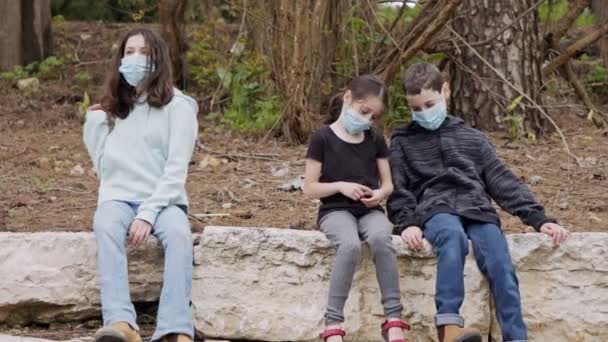 Pandemia de coronavírus - crianças usando máscaras faciais para evitar o contágio sentado entediado — Vídeo de Stock