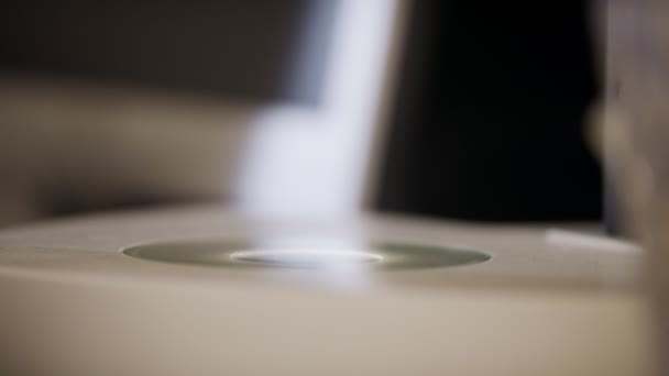 Close-up bij de hand plaatsen van een petrischaaltje onder een microscoop — Stockvideo