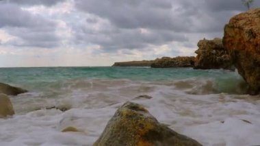 Dalgalar, bulutlar ve kayalar görünümünü