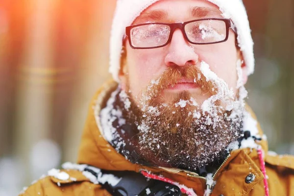 Portret młodego mężczyzny Brodaty zamrożone w Blizzard w lesie. Twarz, broda, wąsy i okulary pokryte szronem. — Zdjęcie stockowe
