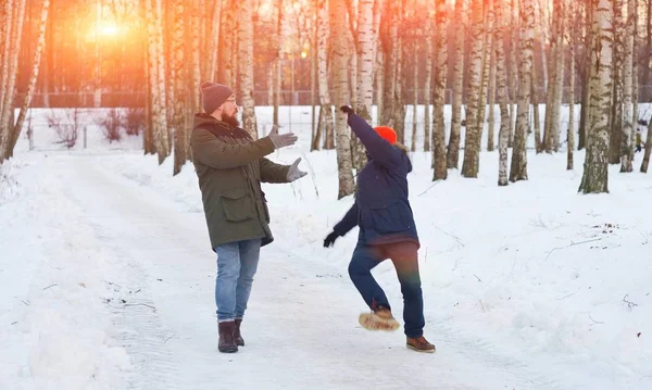Dwóch młodych mężczyzn na spacerze w parku zimowym. Jeden z nich spadł i stracił równowagę, machając rękami, wraca, jego przyjaciel chce jego obsługi. — Zdjęcie stockowe