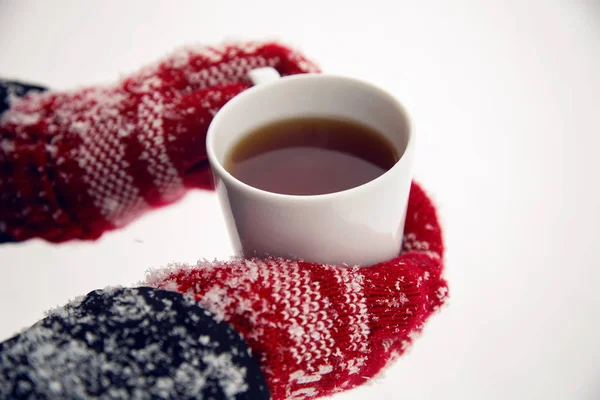 hands in red mittens holding a mug of tea