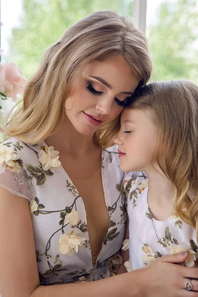 mother kissing daughter in matching dresses