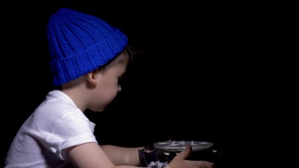 Junge mit blauem Hut und weißem T-Shirt isst eine festliche schwarze Torte