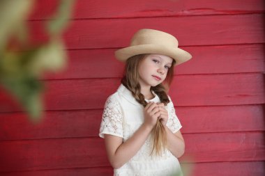 Kızıl saçlı kız beyaz bir şapka kırmızı ahşap duvar arka plan üzerinde elbise