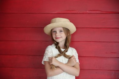 Kızıl saçlı kız beyaz bir şapka kırmızı ahşap duvar arka plan üzerinde elbise